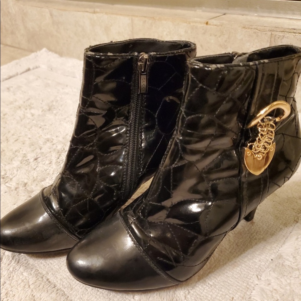 Gucci black patent leather booties with gold buckle detail.